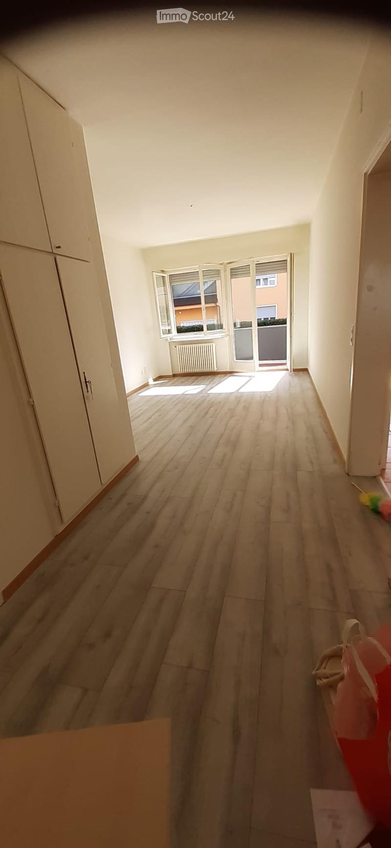 empty room, wooden floor, white walls, sliding glass door, balcony, white cabinets