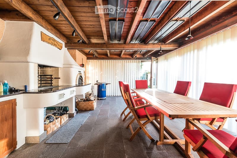 Dining room with a long wooden table, red chairs, wooden ceiling, fireplace, and a counter with a blue trash bin
