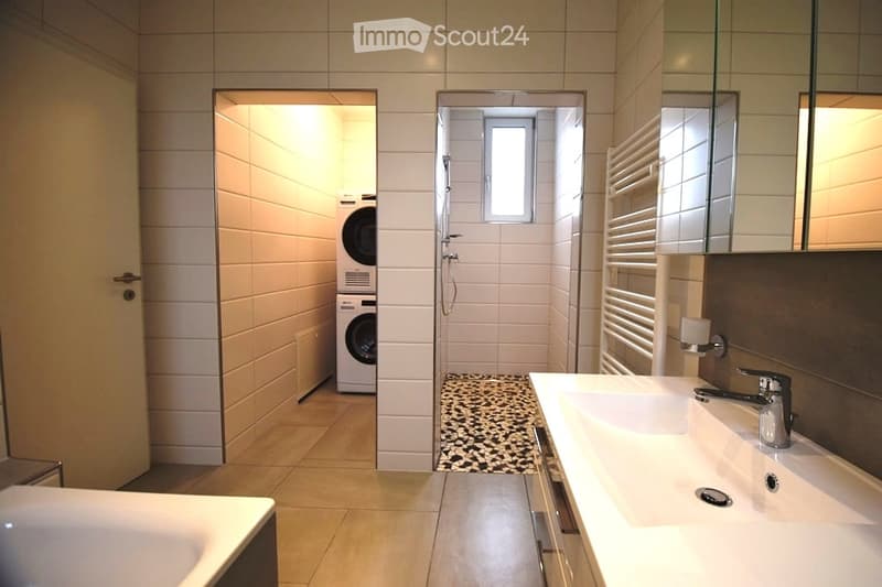 modern bathroom with white tiles, double sink, bathtub, washing machine, shower, radiator