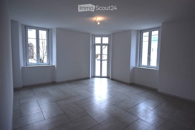 Empty room with white walls, tiled floor, three windows, and a glass door.