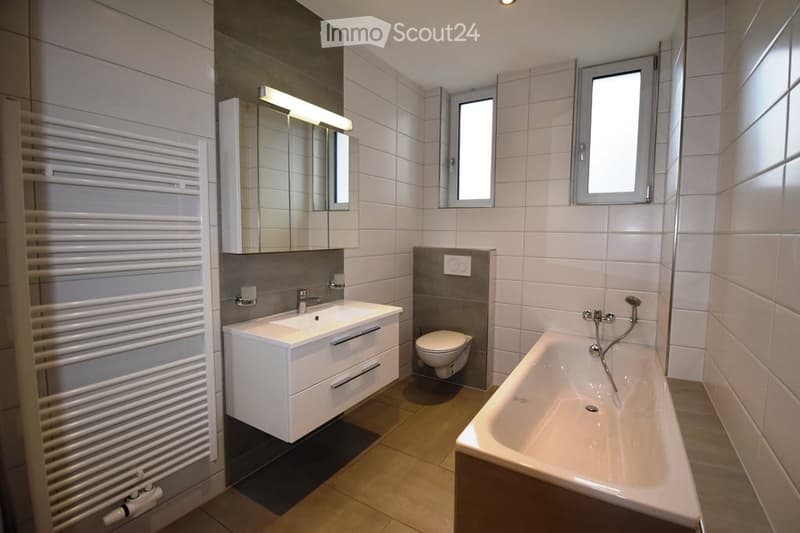 modern bathroom with white tiles, bathtub, sink, toilet, mirror, radiator