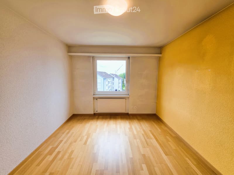 Empty room with wooden flooring, white walls, a window with blinds, and a radiator below the window.