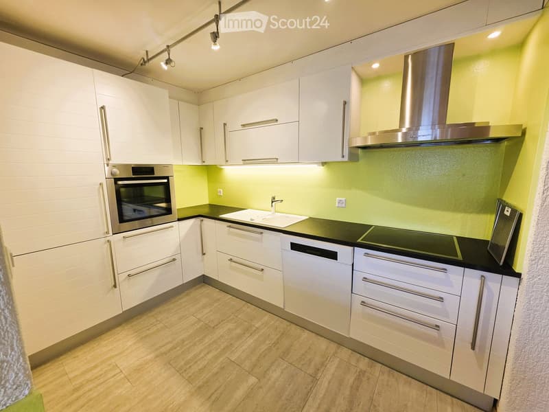 Modern kitchen with white cabinets, stainless steel appliances, and a black countertop.