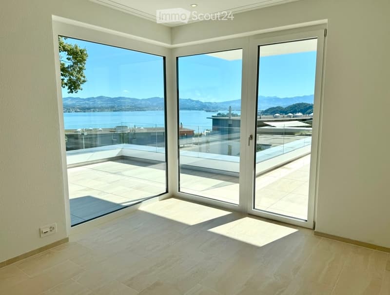 modern interior, large glass sliding doors, wooden flooring, balcony overlooking the sea, scenic mountains in the distance