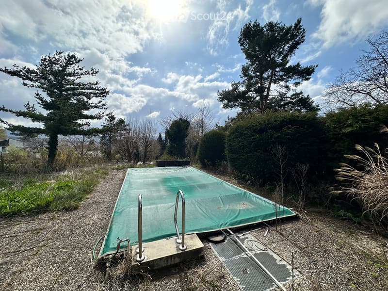 covered swimming pool, gravel ground, metal handrails, bushes, trees