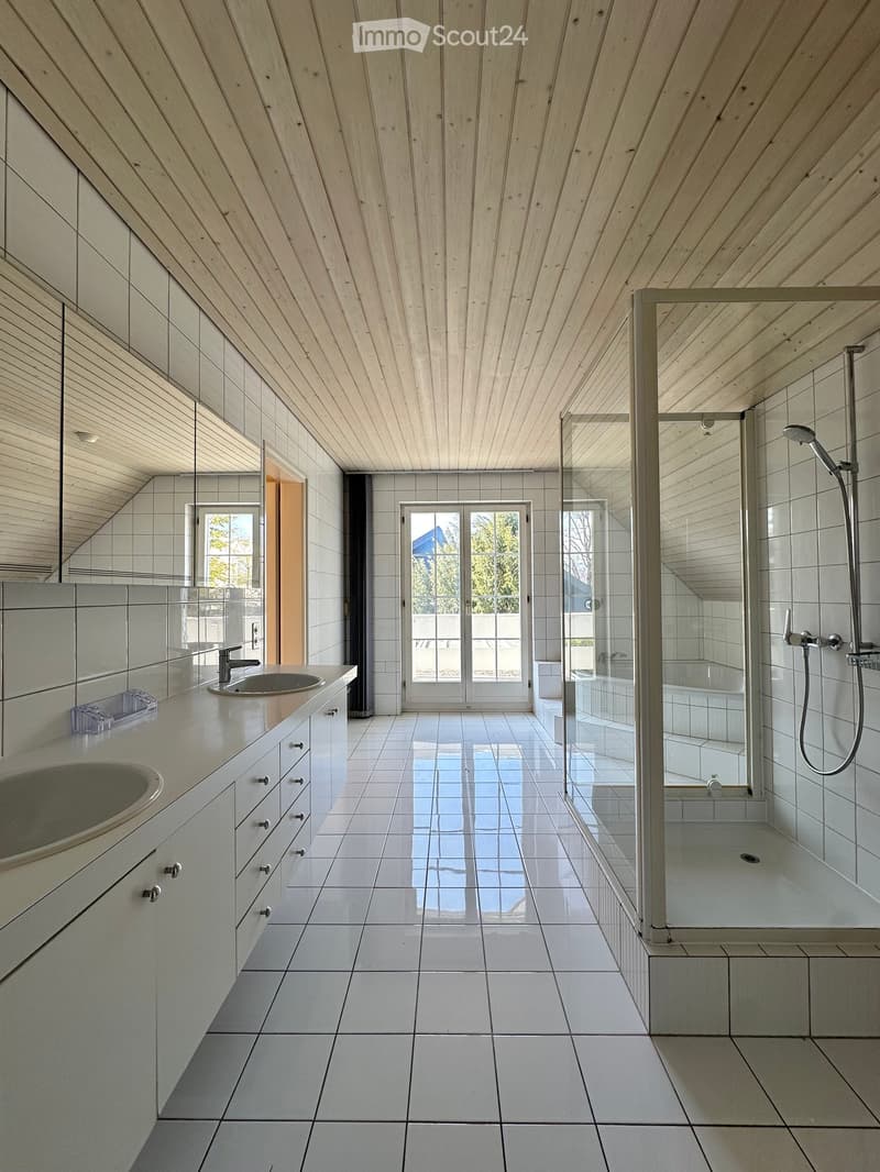 white tiled floor, white tiled walls, two sinks, large mirror, glass shower enclosure, shower head, bathtub