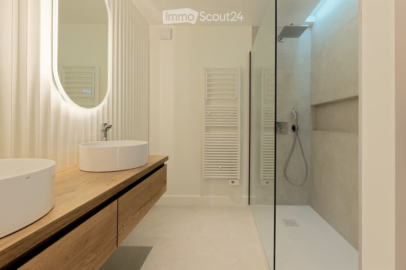 modern bathroom with white sink, wooden countertop, large mirror, glass shower enclosure, white tiles, white towel rack