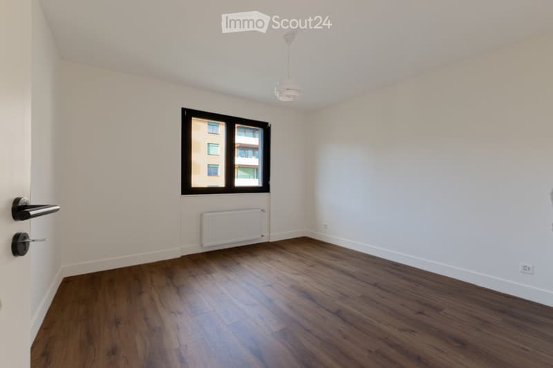 empty room, white walls, wooden floor, white radiator, window, power outlet