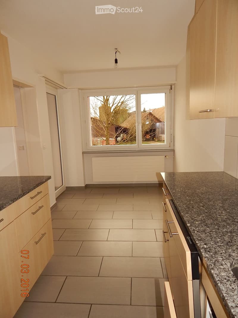 An empty kitchen with a window with a view of the outside