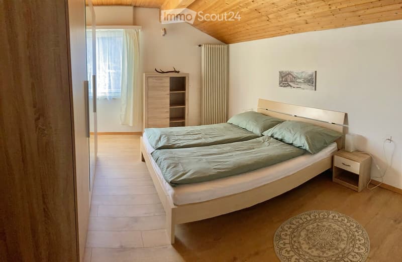 Bedroom with two single beds, wooden floor, wooden ceiling, wooden cabinet, nightstand, rug, window with curtains, picture frame, radiator