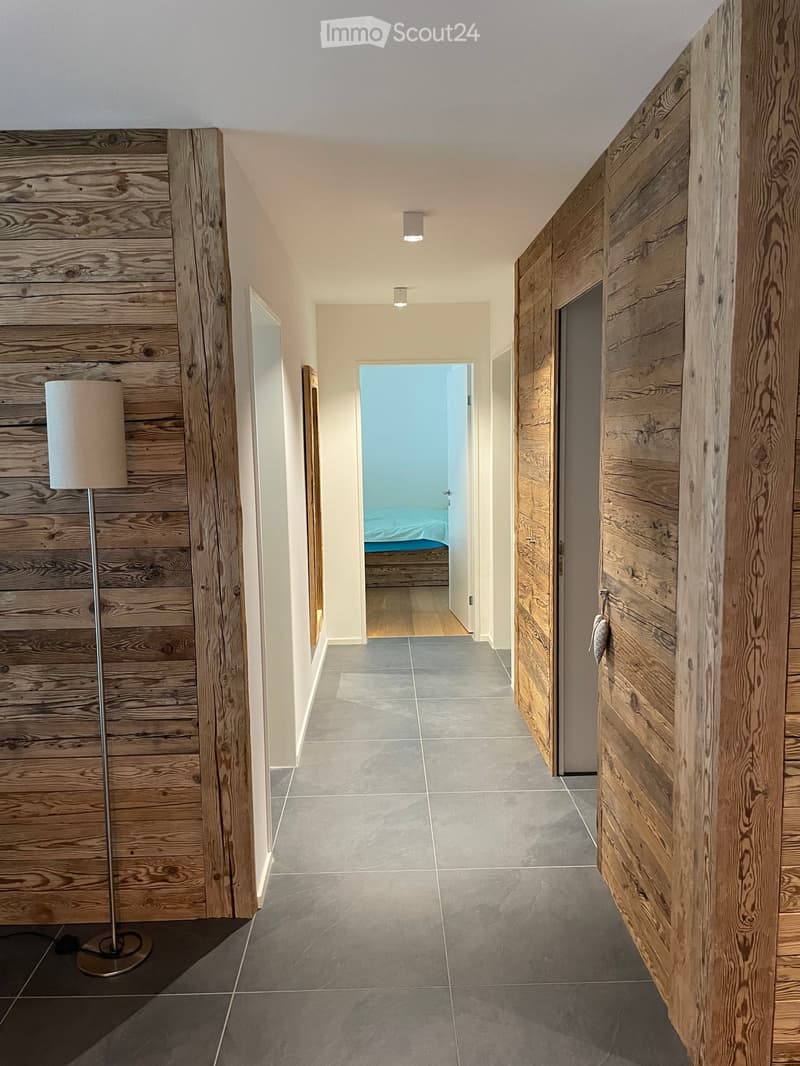 wooden walls, tiled floor, hallway, lamp, open door, bed visible