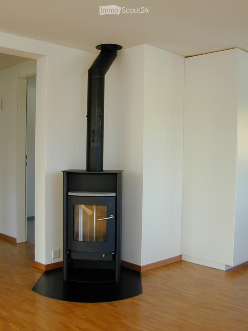 Fireplace in corner, wooden floor, white walls, power outlet