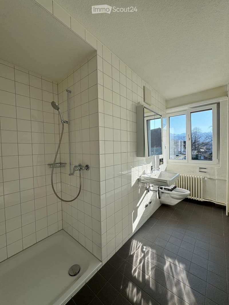 Bathroom with white tiles, shower, sink, toilet, window with view