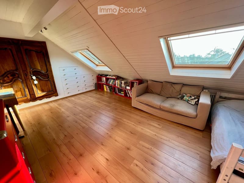 attic room with wooden floor, couch, bed, wooden cabinet, shelves, and windows
