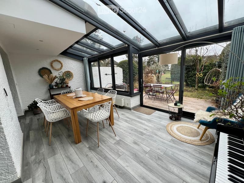 dining area with wooden table and chairs, glass walls, wooden floor, plants, rug, piano