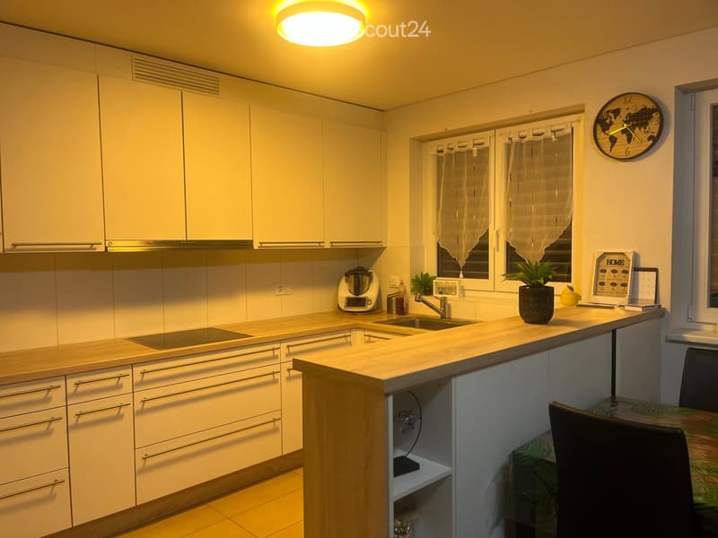 modern kitchen with white cabinets, wooden countertops, integrated appliances, and a small dining area