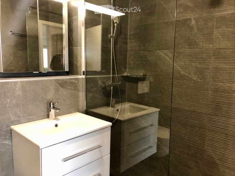 modern bathroom with white sink, mirror, shower, and gray tiles