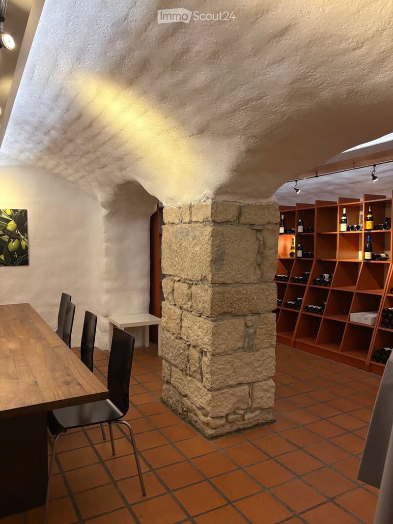 Dining room with wooden table, black chairs, stone pillar, wine rack, picture on wall