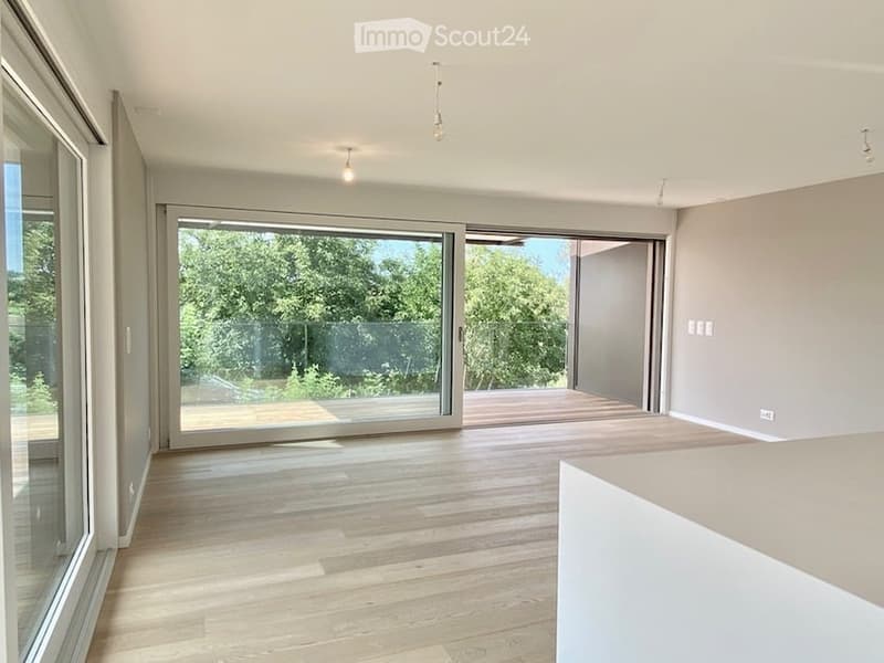 large windows, wooden floor, balcony, sliding glass doors, view of trees