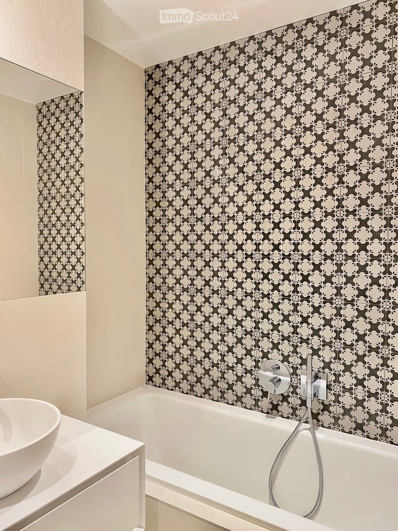 Bathroom with white bathtub, white sink, white cabinet, patterned wall tiles