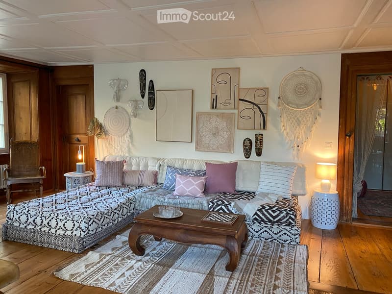 L-shaped sofa, wooden coffee table, chess board, side tables, lamps, rug, wooden floor, wooden doors, wall art