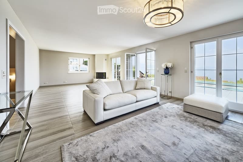 modern living room with white leather couch, glass table, carpet, sliding glass doors, balcony