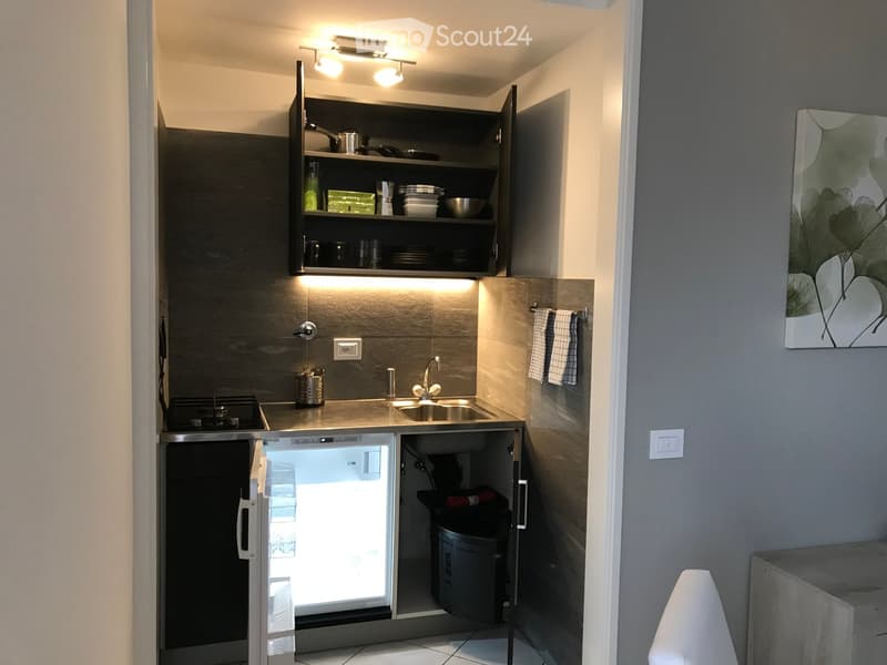 small kitchen with sink, mini fridge, gas stove, cabinets, shelves, power outlets, towel rack