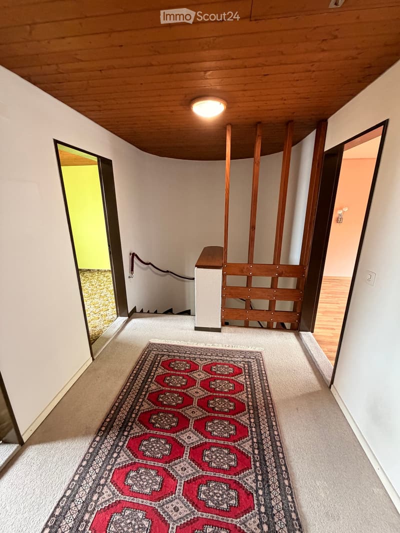 Empty hallway with wooden ceiling, beige carpet, wooden railings, white walls, wooden floor