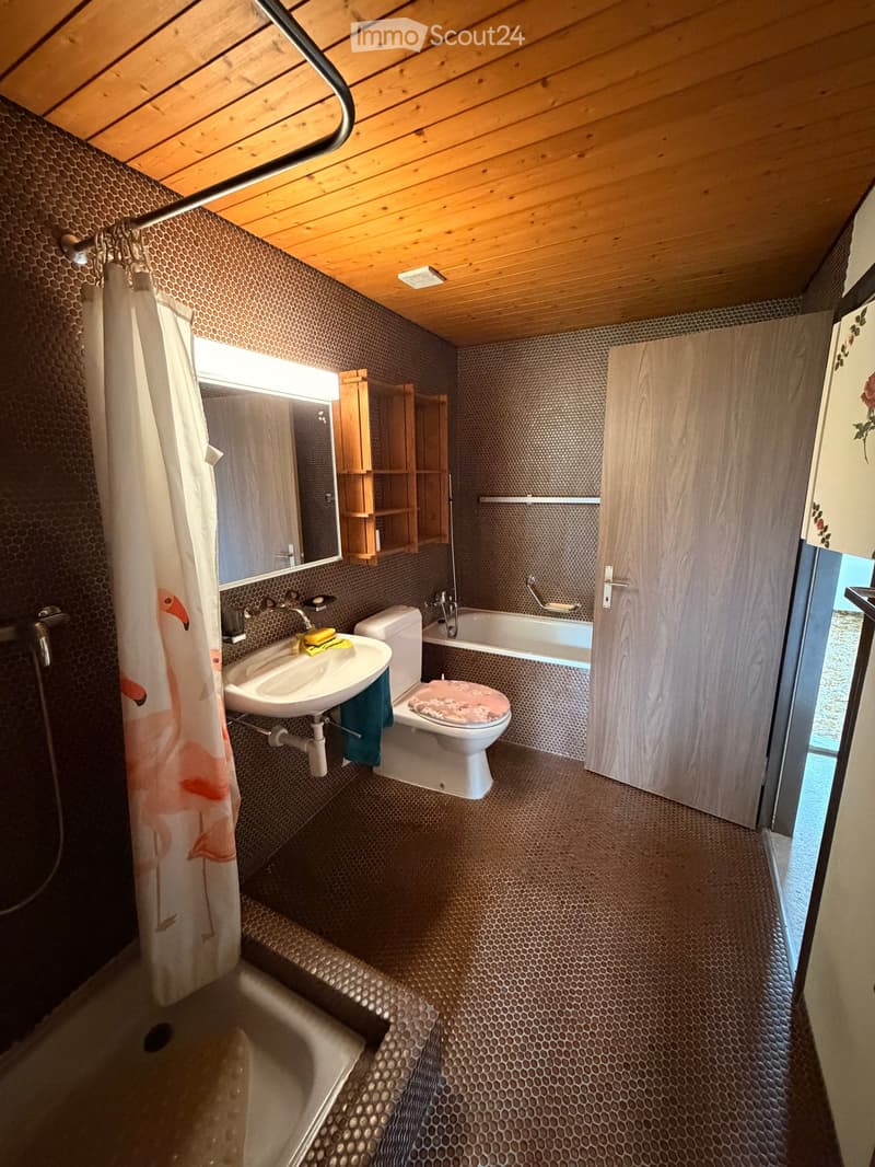 Bathroom with wooden ceiling, bathtub, toilet, sink, shower curtain, wooden shelves, mirror, and a door