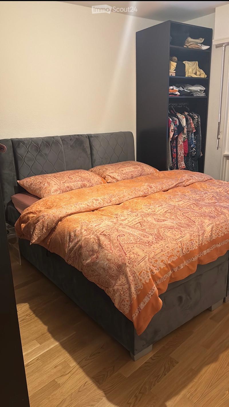 A bedroom with a bed, a wardrobe, and a wooden floor