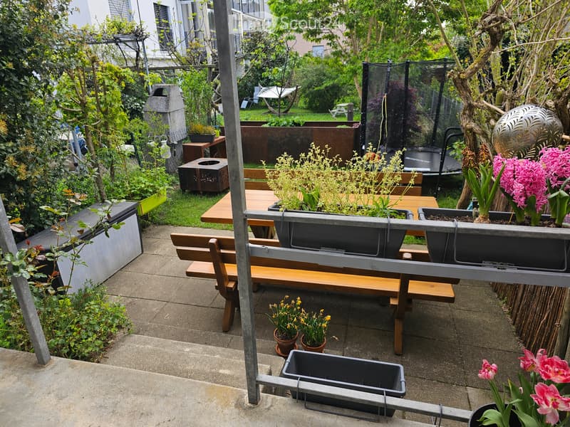Wooden bench, wooden table, potted plants, flowers, trampoline, metal fence, metal railing, concrete floor, metal poles