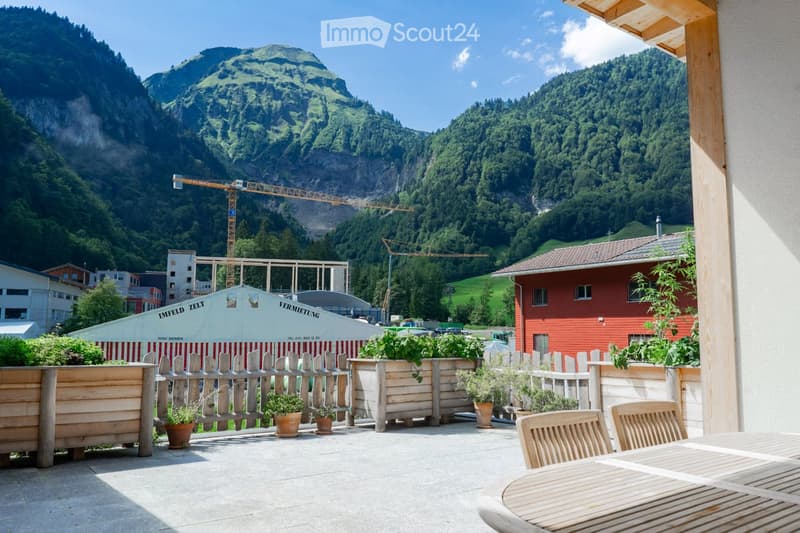 patio with wooden table and chairs, white tents in the background, mountain landscape