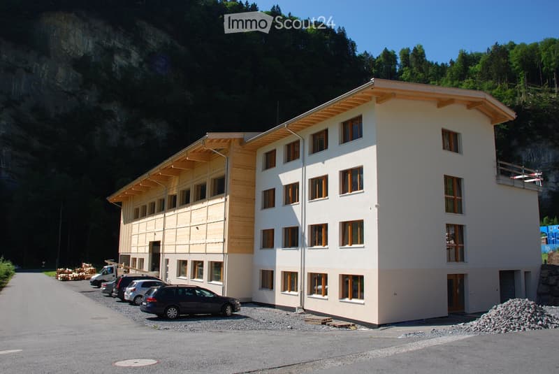 multi-story residential building, wood trim on first floor, multiple cars parked in front