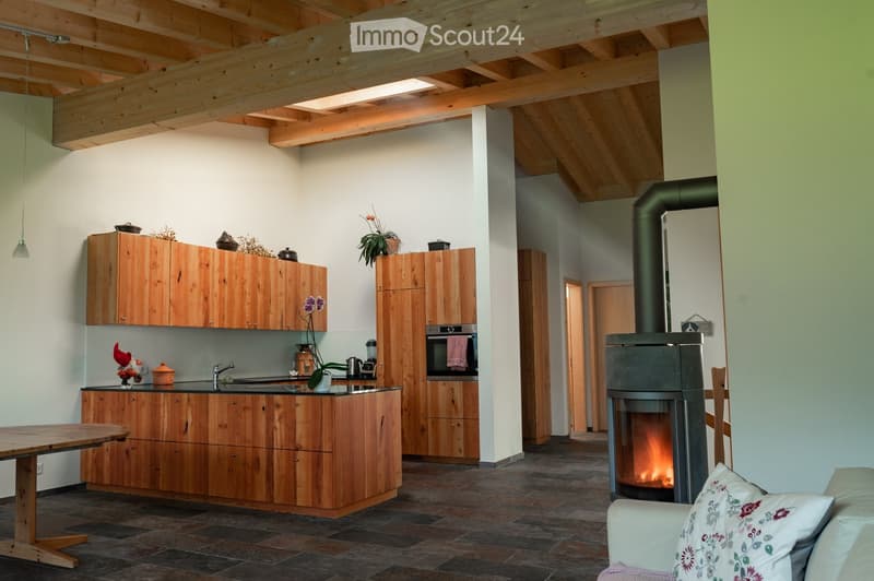 open kitchen with dining table, modern fireplace, wooden cabinets, white and green walls, hanging light, modern furniture