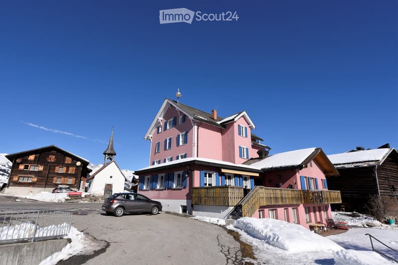 pink house, wooden balcony, snow on the roof, car parked in front