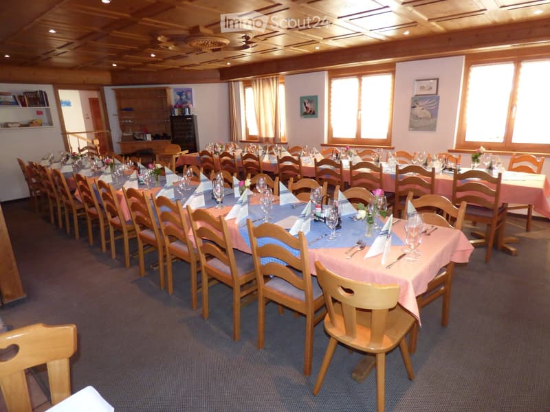 Dining room with long tables, wooden chairs, pink tablecloths, wine glasses, and flower arrangements