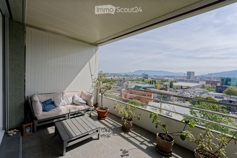 Balcony with couch, coffee table, potted plants, and a view of the city