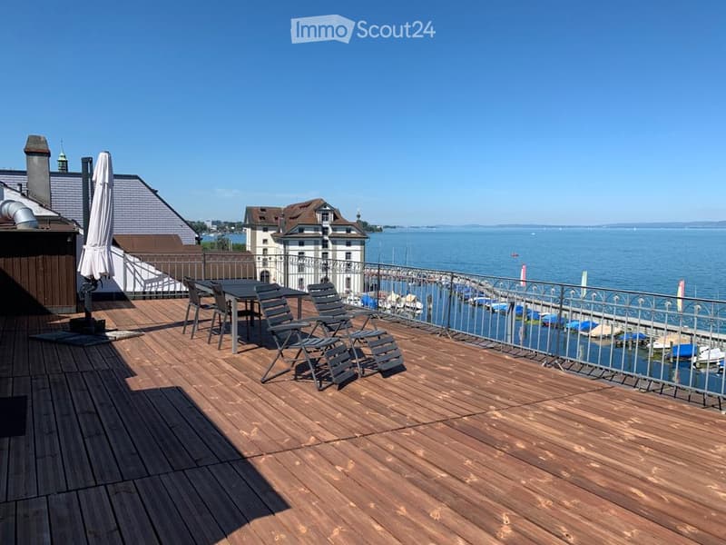 wooden deck, table and chairs, closed umbrella, metal railing, lake view