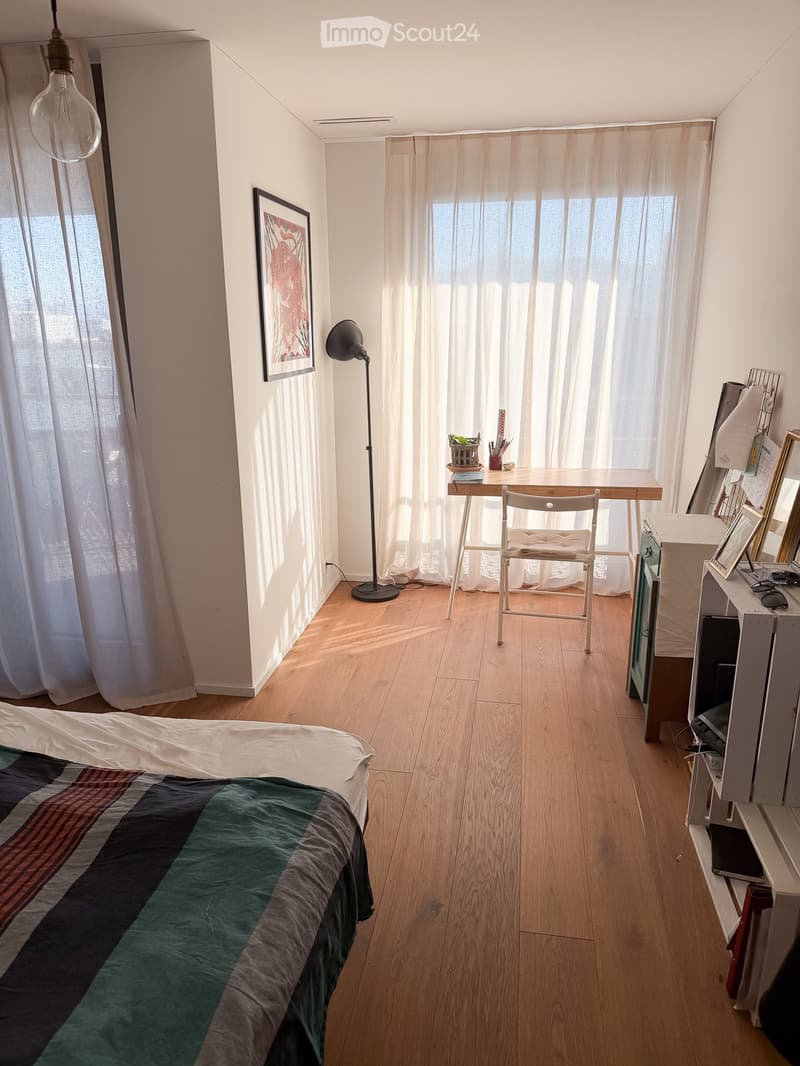 bedroom with bed, desk, chair, lamp, picture frame, curtains, wooden floor