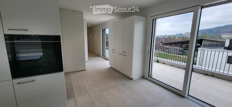 modern kitchen with white cabinets, black oven, wooden floor, sliding glass door to balcony