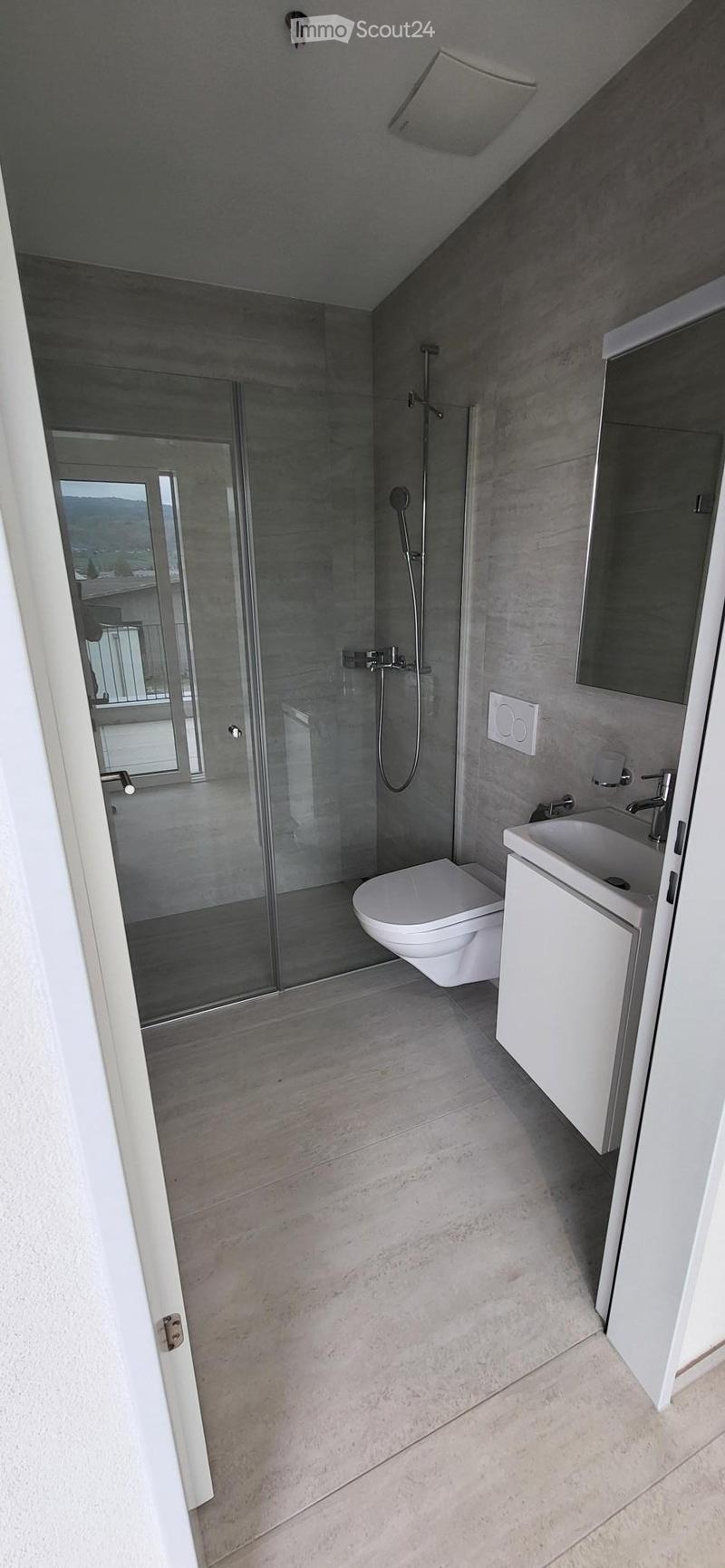modern bathroom with glass shower, white toilet, white sink, mirror, white cabinet, tiled floor