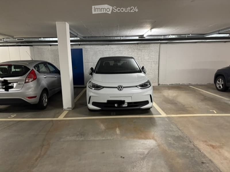 underground parking lot with three cars parked, white walls, yellow markings