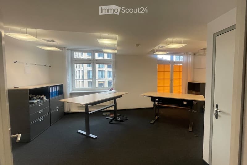 empty room with two desks, cabinets, windows, and ceiling lights