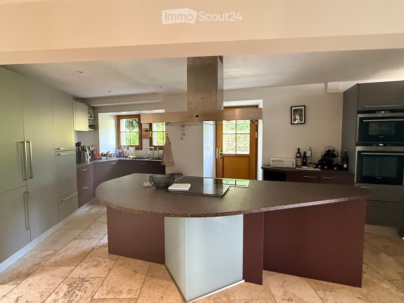 modern kitchen with island, gas stove, refrigerator, cabinets, microwave, wine rack, picture frame, wooden door