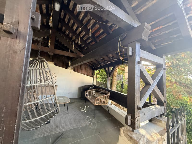 wooden beams, hanging lamps, wicker furniture, tiled floor, outdoor seating