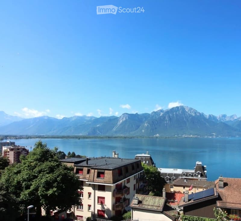 Aerial view of a building with a lake and mountains in the background