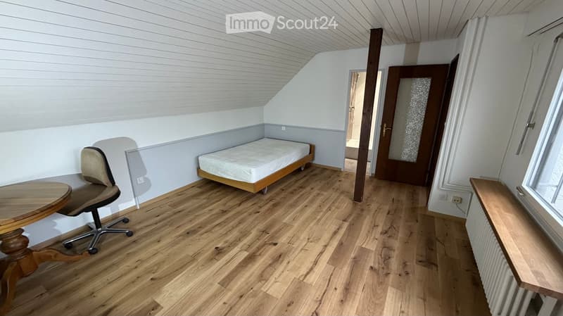 bedroom with a bed, wooden floor, wooden chair, small table, shower room, radiator