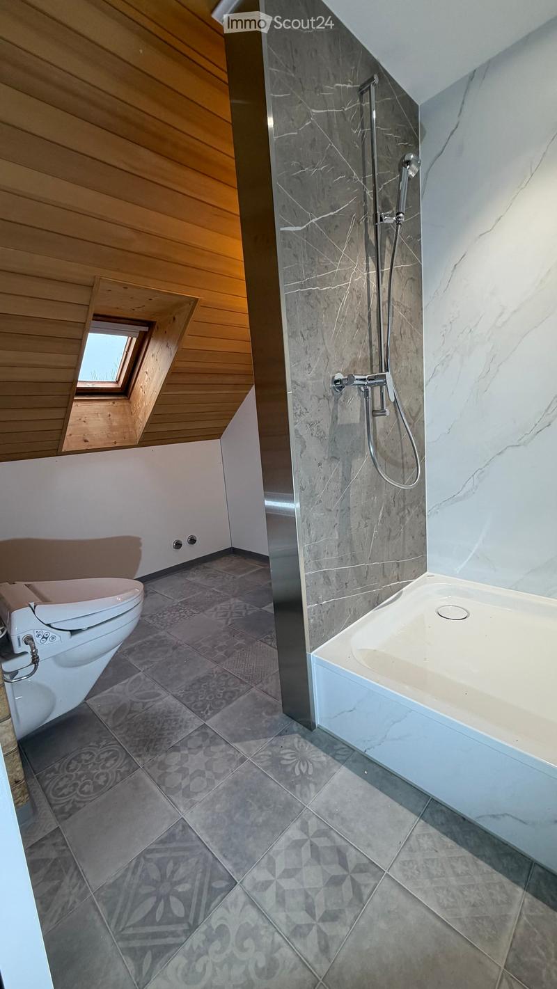 Bathroom with tiled floor, toilet, shower area, and ceiling light.