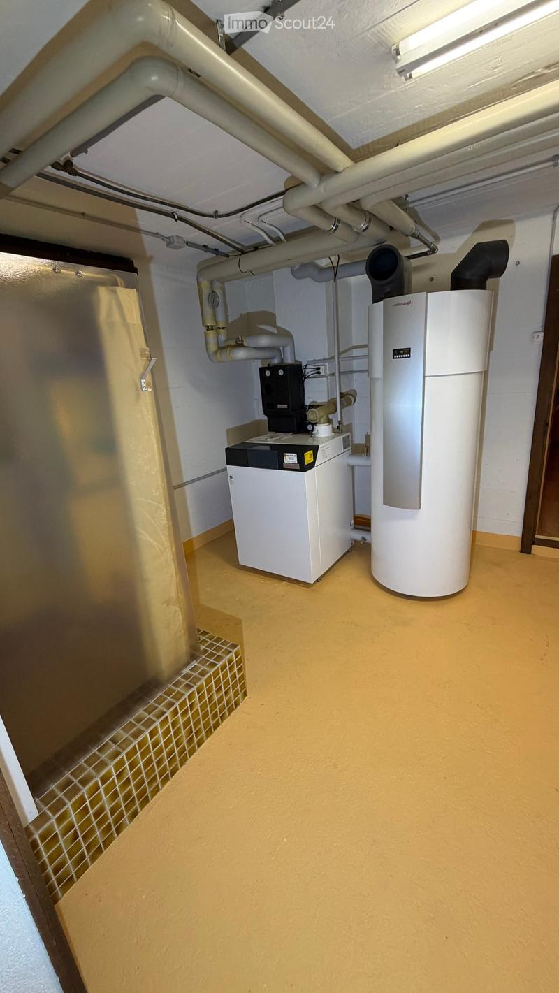 underground utility room, tiled step, white tiled floor, yellow walls, ceiling with pipes, large washing machine, water tank, water heater