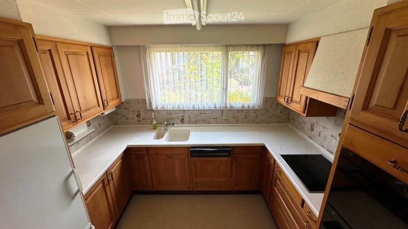 wooden cabinets, white countertops, sink, dishwasher, refrigerator, oven, window with curtains